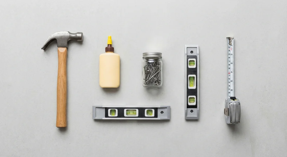 Sélection d'outils pour réparer un meuble : marteau, clous et colle à bois.